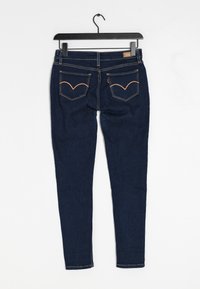 Mörkblå denimjeans med en figursydd design, som har två bakfickor med orange sömnadsdetaljer och en standard midja.