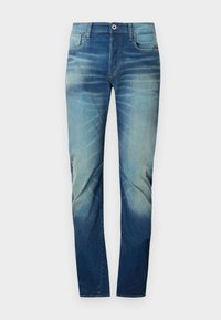 Jeans i denim med ett gradient blått färgschema, med en klassisk femficksdesign, hållbara sömmar och en knappstängning vid midjan.