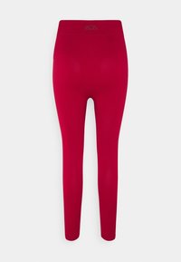 Czerwone legginsy wykonane z elastycznego materiału, z szerokim, elastycznym pasem w talii. Gładka faktura bez widocznych wzorów czy ozdób.