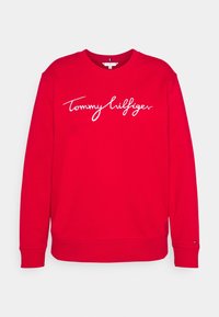 Czerwony bawełniany sweatshirt z długimi rękawami, ściągaczami przy mankietach i u dołu. Posiada biały haftowany logo "Tommy Hilfiger" na przodzie.