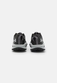 Chaussures de sport noires au design léger, avec une semelle extérieure grise texturée et des accents réfléchissants. Anses au talon pour un enfilage facile.