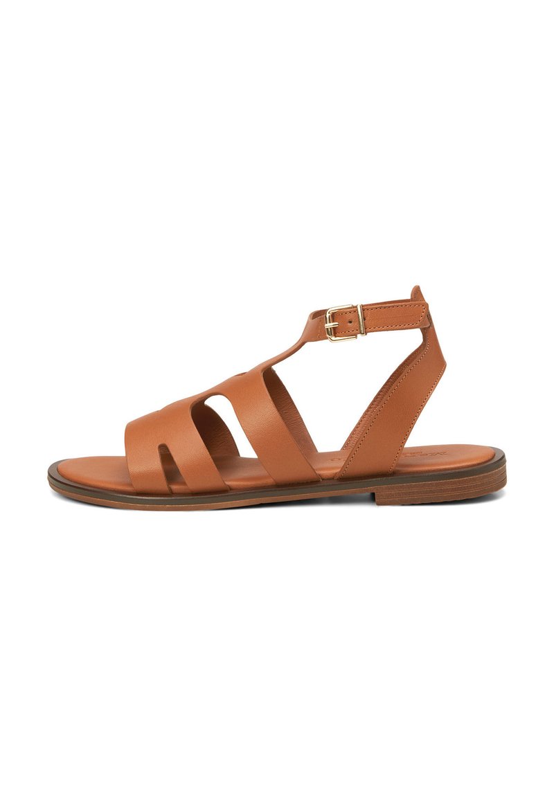 Brown leather sandal with a cutout design, adjustable ankle strap, and gold buckle. Flat sole with minimal texture and smooth finish.