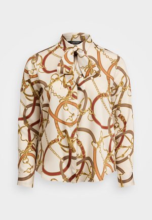 Blusa de seda con un estampado de cadenas y tiras en oro, rojo y marrón sobre un fondo crema. Incluye un lazo en el cuello y cierre de botones.