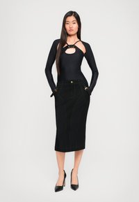 Bodysuit preto de manga longa com um recorte e detalhe em nó, combinado com uma saia lápis de ganga preta com detalhes em dourado e costuras em contraste.