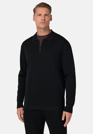 Schwarzer Zip-Pullover aus weichem Stoff, mit Kragen, langen Ärmeln und figurschmeichelndem Schnitt. Glatte Textur und minimales Design.