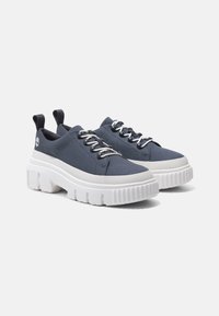 Tmavě modré plátěné tenisky s bílou silnou podrážkou, zdobené texturovanými detaily, plochými tkaničkami a poutky na patě pro snadné oblékání.