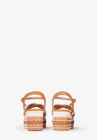 Tan leather sandals with an ankle strap and woven espadrille-style sole. Sole features a braided texture and white accent stitching.