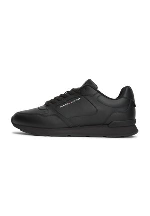 Sort low-top sneaker med snørebånd foran, glatte og teksturerede paneler og "Tommy Hilfiger"-logo på siden.