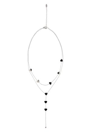 Colier delicat din lanț de argint cu straturi suprapuse și pandantive alternante mici în formă de inimă, negre și argintii, cu un pandantiv în formă de inimă pendulant.