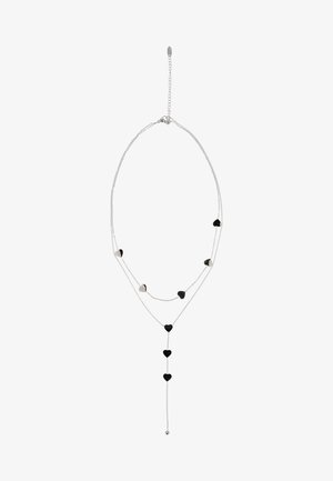 Finom ezüstlánc, rétegezett szálakkal és váltakozó kis fekete és ezüst szívmedálokkal, amelyek között egy lelógó szívmedál is található.