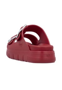 Red rubber sandals with a thick sole, cut-out design, and metallic buckle detail on the strap. Smooth texture and rounded shape.
