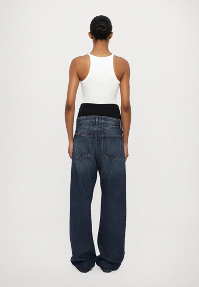 Jeans in denim blu a gamba larga con una cintura elastica nera, caratterizzati da un classico design a cinque tasche e una finitura sbiadita.