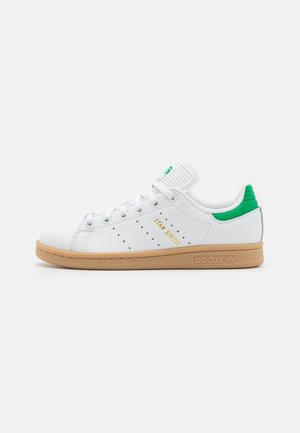 Hvid Adidas Stan Smith-sneaker med grøn hælkappe, gyldent "Stan Smith"-tekst på siden og gummisål, vist fra ydersiden.