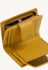 Portefeuille en cuir jaune avec une finition texturée, un compartiment zippé, des emplacements pour cartes et une fenêtre transparente pour l'identification. Présente une fermeture à bouton-pression.