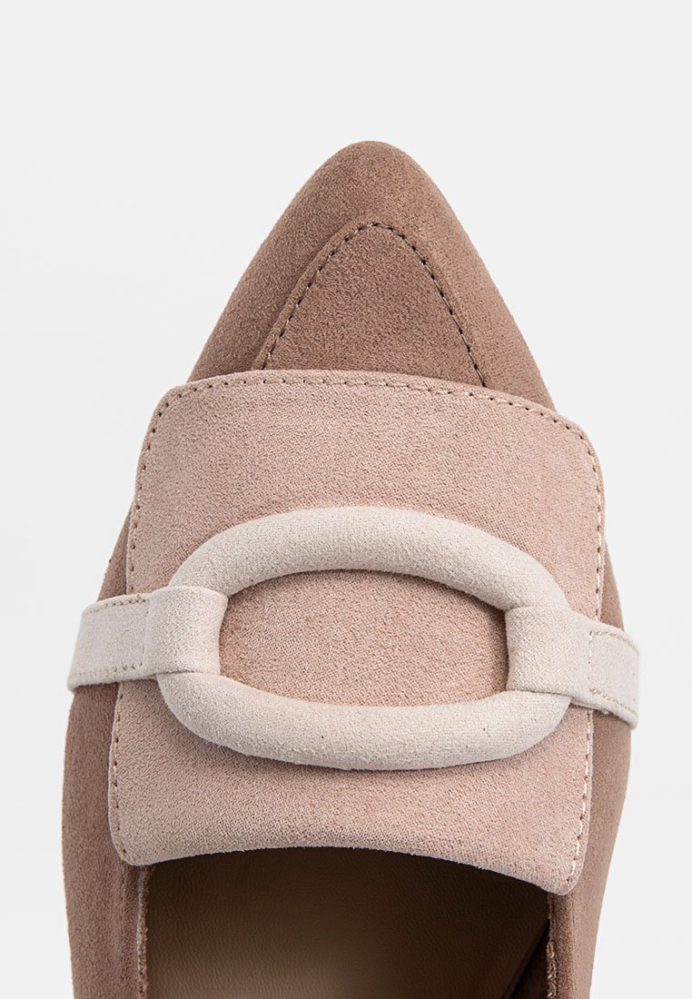 Chaussure à bout pointu en suède bicolore beige et taupe clair. Dispose d'une large sangle avec une boucle ovale douce et des détails de broderie. Semelle plate.