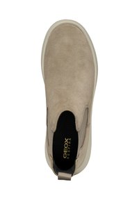 Chaussure slip-on beige avec une tige en daim, panneaux latéraux élastiques et une semelle de couleur crème. Texture lisse avec un intérieur rembourré et un détail de logo.