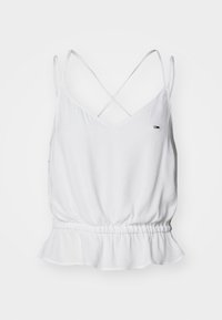 Haut blanc sans manches avec fines bretelles croisées, taille élastique, ourlet subtilement volanté et petit logo rectangulaire sur la poitrine.