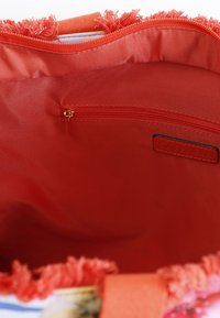 Rode stoffen tote bag interieur met een ritssluiting zak, met een gladde textuur en uitgerafelde bovenranden. Bevat een label met de opdruk "Cab noir."