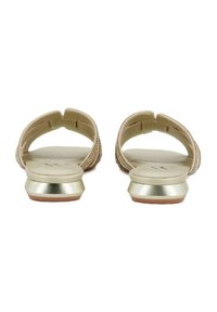 Sandali piatti beige con un design a fascia testurizzata e un accento dorato metallico sul tallone. Sottopiede liscio senza loghi visibili.