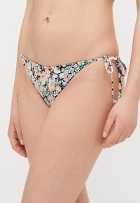 Kwiatowe majtki bikini z wiązaniami po bokach, z ciemnym tłem i wielokolorowym wzorem kwiatów, głównie w pastelowych odcieniach.