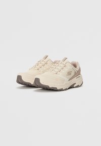 Baskets beige clair en mesh et matériau synthétique, semelles texturées, design à lacets et logo discret sur le côté et le talon.
