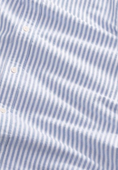 Tissu à rayures verticales bleues et blanches avec trois boutons blancs, montrant des plis doux et une texture.