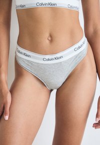 Calvin Klein kvinners thong i grå bomull med en myk elastisk midjebånd som har en logo i svart og hvitt. Enkel, tettsittende design.
