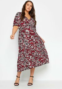 Blumenkleid in Midi-Länge mit V-Ausschnitt, kurzen Ärmeln, kräftigen roten und weißen Blumenmustern sowie einem fließenden Rock mit Rüschensaum.