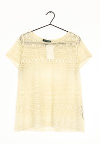 Kortärmad crèmelace-topp med blommönster och geometriska mönster, hängande på en svart trådhängare mot en vit bakgrund.