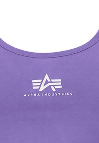 Lilla tanktop laget av myk stoff med rund hals og en hvit logo med striper og teksten "ALPHA INDUSTRIES" i sentrum.