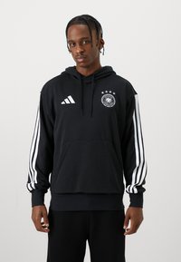 Czarna bluza z kapturem, z sznurkiem, kieszenią z przodu, białymi paskami adidas na rękawach oraz z niemieckim emblematem piłkarskim z gwiazdami na piersi.