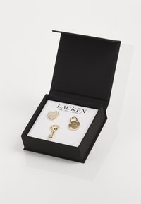 Set di gioielli in tonalità oro, custodito in una scatola nera, caratterizzato da un ciondolo a forma di cuore con decorazioni simili a perle, un pendente a forma di chiave e un ciondolo a forma di lucchetto rotondo.