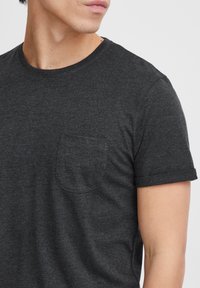 T-shirt à manches courtes gris charbon en coton doux, avec un col rond et une petite poche sur la poitrine gauche.