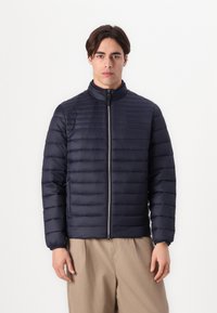 Σακάκι από ναυτικό ύφασμα με κατακόρυφο ραμμένο σχέδιο, ψηλό γιακά και κλείσιμο με φερμουάρ. Λείο ύφασμα με ελαστικές μανσέτες για εφαρμοστή εμφάνιση.