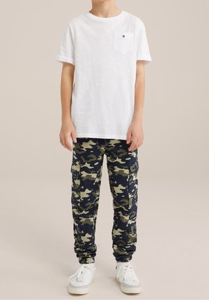 Biała bawełniana koszulka z kieszenią i okrągłym dekoltem, zestawiona z granatowo-zielonymi moro spodniami typu cargo z bocznymi kieszeniami i elastycznymi mankietami.