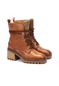 Botas de tobillo de cuero marrón con un cuello de tela texturizada, parte delantera con cordones, ojales dorados y un tacón de bloque de madera grueso.