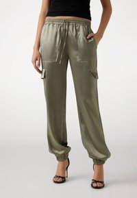 Pantaloni cargo in satin verde oliva con polsini elastici, vita con cordoncino, e quattro tasche. Tessuto morbido con una vestibilità comoda.