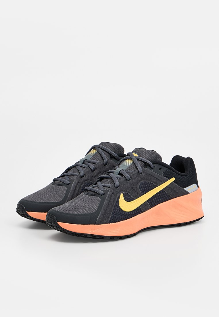 Para czarno-szarych butów do biegania Nike z żółtym logo i pomarańczowymi podeszwami na białym tle.