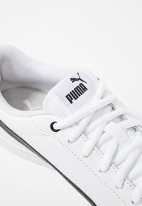 Weißer Sportschuh mit strukturiertem Lederoberteil, schwarzen Akzenten, Schnürsystem und Puma-Logo auf der Zunge. Leicht gepolsterter Kragen.