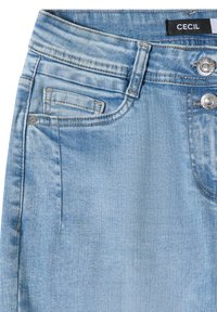 Jean en denim bleu clair avec poches avant, boutons métalliques, passants de ceinture et une étiquette noire portant l'inscription "CECIL" à la taille.