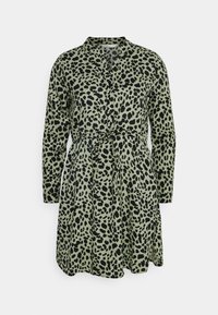 Grøn kjole med sort leopardprint, lange ærmer, krave og bælte i taljen. Har en knaplukning foran og plisseret nederdel.