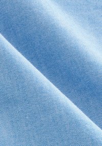 Tissu bleu clair avec une texture lisse, présentant un motif tissé subtil de petits points. Le tissu se drape délicatement en pli.