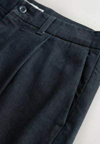 Dark blue trousers made of denim, featuring a flat front with pleats, a single button closure, and angled side pockets.