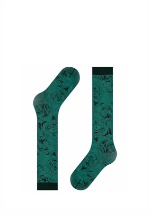 Calcetines verdes hasta la rodilla con un patrón floral negro y puños, talones y dedos sólidos en negro, mostrados planos con un calcetín doblado.