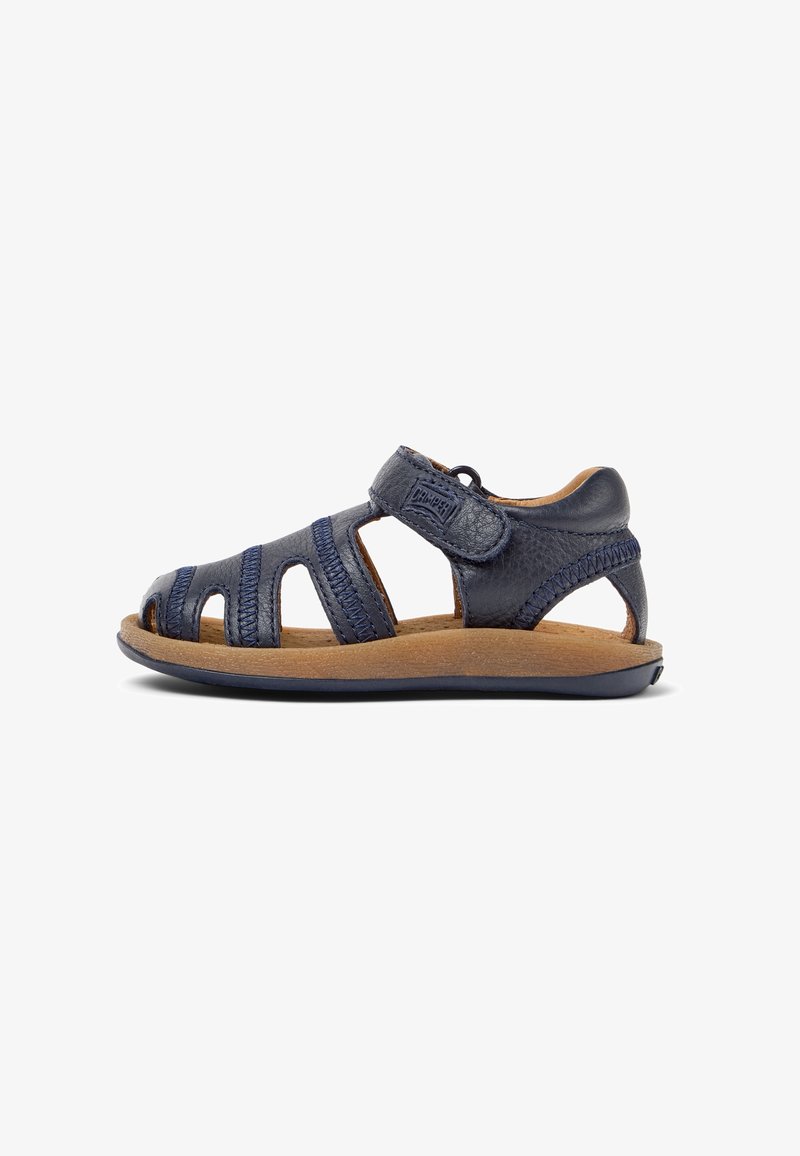 Sandale enfant en cuir bleu marine avec brides découpées, fermeture Velcro, semelle intérieure beige rembourrée et semelle noire souple, vue de côté.