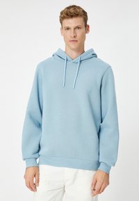 Sudadera de color azul claro hecha de tela suave, con capucha ajustable, puños acanalados y un diseño de corte relajado.