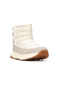 Botín blanco y esponjoso con parte superior acolchada, acentos beige, suela de goma y agarre texturizado. Cuenta con un zipper lateral y una lengüeta para facilitar su uso.