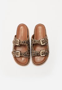 Brown leather slide sandals with leopard print straps, gold buckles, and small gold studs on a white background.