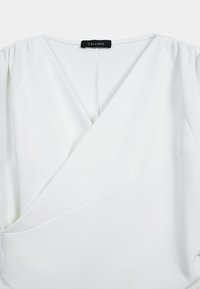 Blouse blanche à enrouler avec un décolleté en V et des manchesGathered, dotée d'un tissu doux légèrement extensible et de détails de coutures diagonales subtiles.
