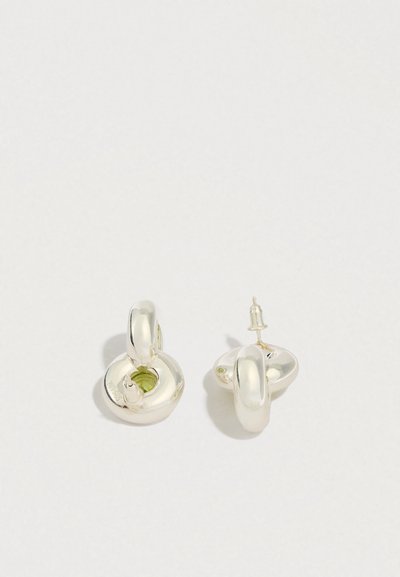 Hopeiset korvakorut, joissa on pyöreä, kaksinkertainen lenkkimuotoilu ja pieni vihreä yksityiskohta. Pinta on kiillotettu ja heijastava.